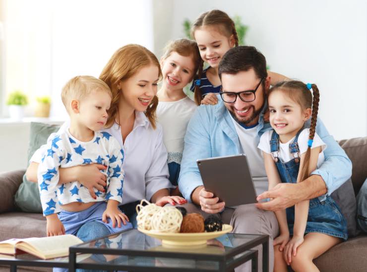 Famiglia con 4 figli sorride guardando un iPad
