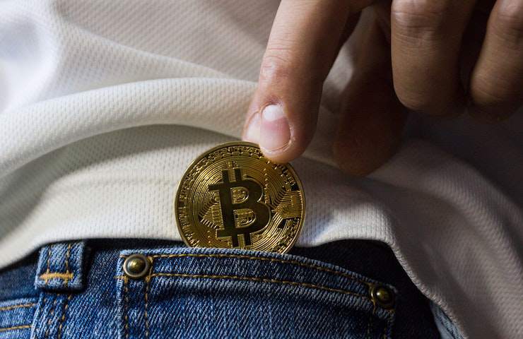 Un bitcoin fisico messo in una tasca di un jeans da qualcuno