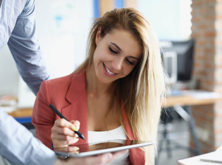 Una donna sorride mentre appone la sua firma su di un iPad