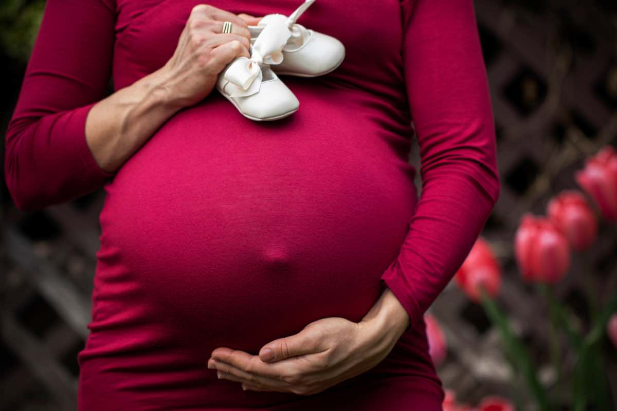 Una mamma col pancione e due scarpine da bambina