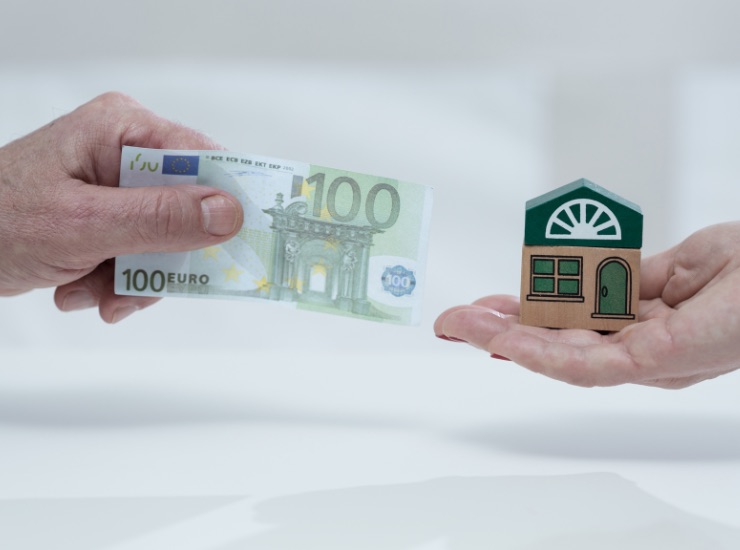 Una banconota da 100 euro accanto a una casa stilizzata